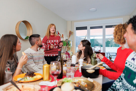 Woman making toast during christmas dinner celebration with family