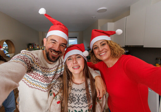 Happy family wearing santa hats taking christmas selfie