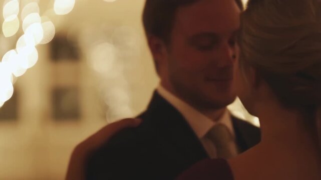 Intimate close embrace of couple at formal evening event with warm bokeh lighting, visible hand on shoulder, elegant styling, soft profile view, refined mood, glowing ambiance, and romantic connection
