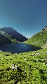 Idyllic mountain scenery with lush green meadows and deep blue mountain lake in the Alps