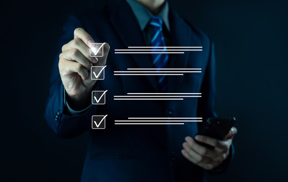 Businessman checklist concept as clipboard document checklist form on the virtual screen Use your hands or a pen to check the correct control gaps and check the quality standards of the work.