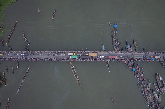 Sirajganj, Rajshahi Division, Bangladesh - 19 September 2025: Aerial view of a traditional boat race with long wooden boats on the river and crowds of people on the bridge.