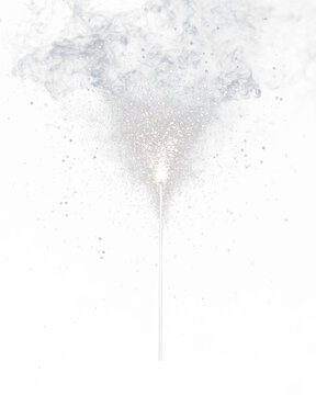 A lone, upright sparkler emits a vibrant cloud of sparkling light against a grey backdrop