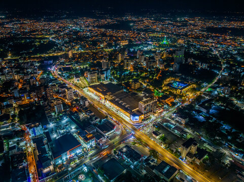 Santiago de los Caballeros, Dominican Republic - 29 December 2025: Aerial view of Agora Santiago Center illuminated at night, surrounded by vibrant city lights and urban buildings.