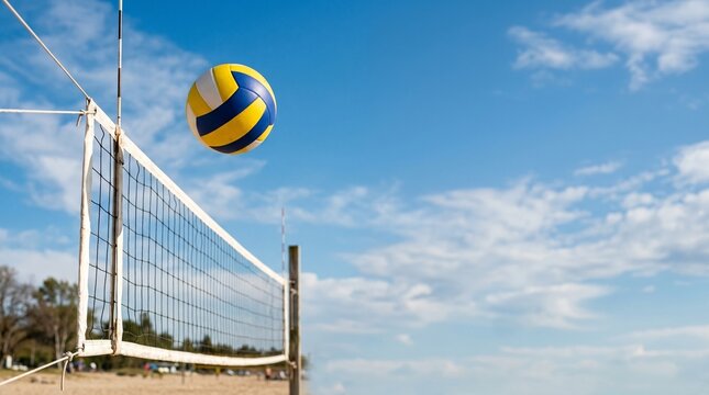 A vibrant yellow and blue volleyball caught mid-flight above a white net on a sunny sandy beach, under a clear blue sky, perfect for summer sports and outdoor recreation