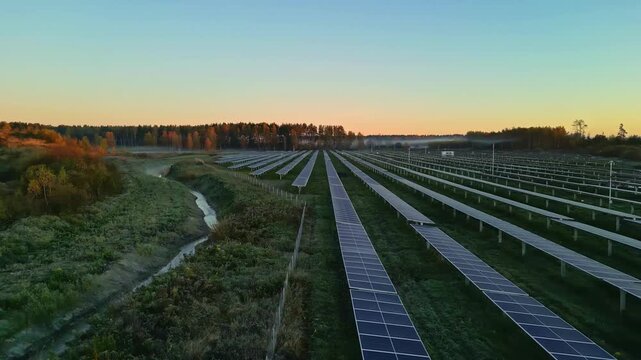 Aerial view of solar farm with rows of photovoltaic panels in a field at sunrise in Riga, Latvia.