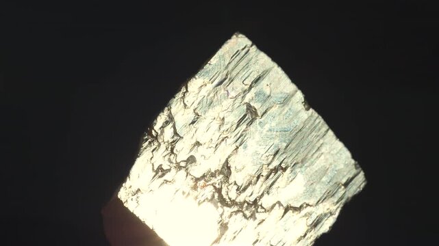 A cubic crystals of pyrite, with some surfaces showing characteristic striations, isolated on a black background