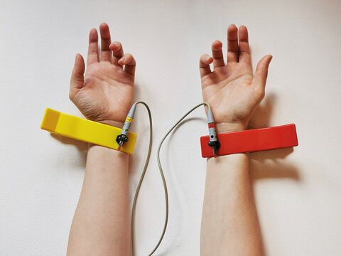 Two human hands with ECG electrode on wrist, heart health check, pulse diagnostics