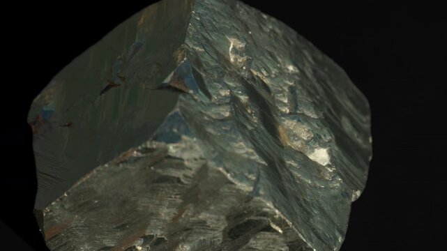 A cubic crystals of pyrite, with some surfaces showing characteristic striations, isolated on a black background