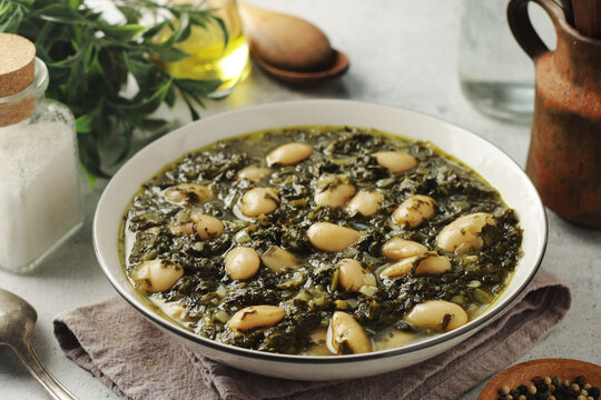 A bowl with traditional Tuscan kale salad and white beans soup Cavolo nero e fagioli