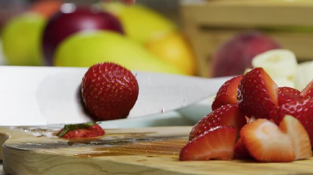 Sharp knife dicing up strawberries on cutting board - closeup shot