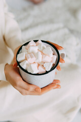 Obraz premium Woman holding white cup filled with heart shaped marshmallows. Cozy comfort atmosphere during Christmas holiday season. Delicious sweet hot drink for winter relaxation and love celebration.