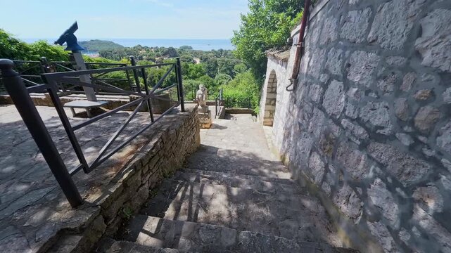 View of stone staircase leading down towards the sea with historic stone walls and metal railings in Vrsar, Istria County, Croatia.