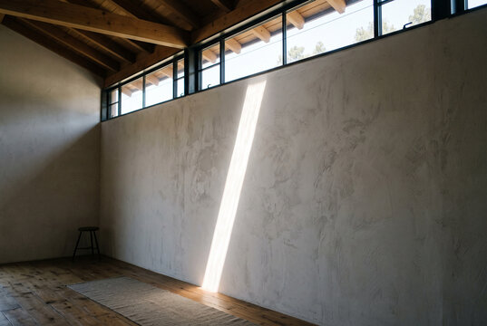 Clerestory window near ceiling casting narrow light band across interior wall