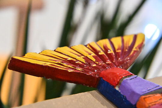 handcrafted wooden fish tail sculpture close up, painted yellow and red artisanal fish caudal fin detail, vibrant brazilian folk art craft exhibit with copy space