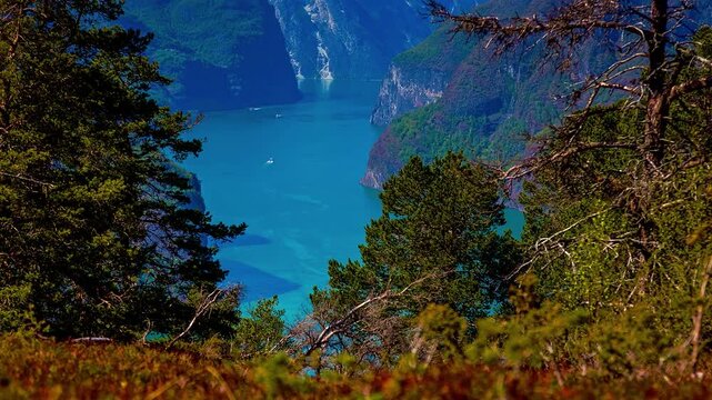 View of Aurlandsfjord with steep mountains and a small boat on the water in Flam, Vestland, Norway.