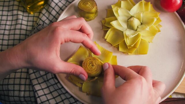 Close-up of hands opening and flattening a fresh artichoke before frying. Traditional Spanish flor de alcachofa preparation. High quality 4k footage