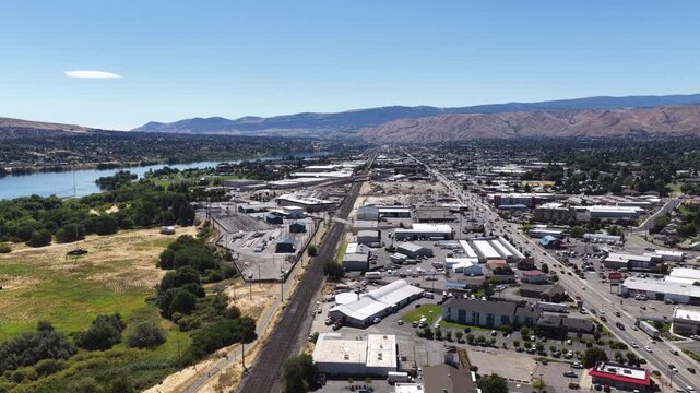 Aerial of industrial and commercial waterfront area in Wenatchee Washington with extensive railroad tracks running parallel to the Columbia River surrounded by warehouses