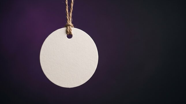 Blank round paper tag hanging by a twine string against a dark gradient background