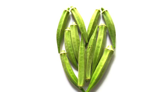 Fresh raw green okra pods arranged in a heart shape isolated on clean white background in Guatemala