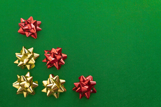 Red and gold decorative bows on green background with space for text