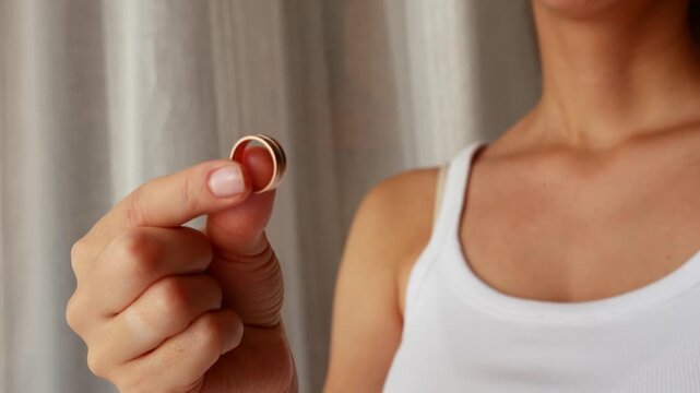 Close up of woman holding wedding ring after breakup at home