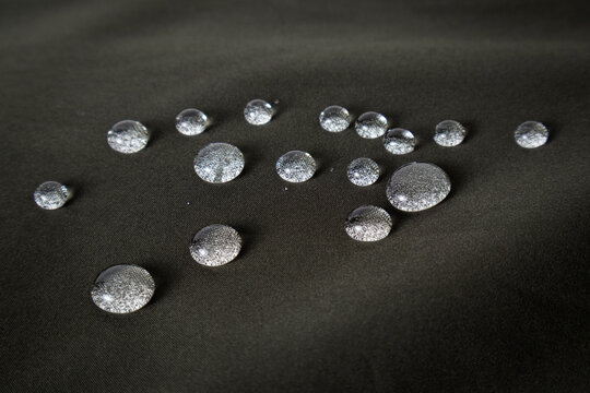 Black waterproof fabric with waterdrops close-up