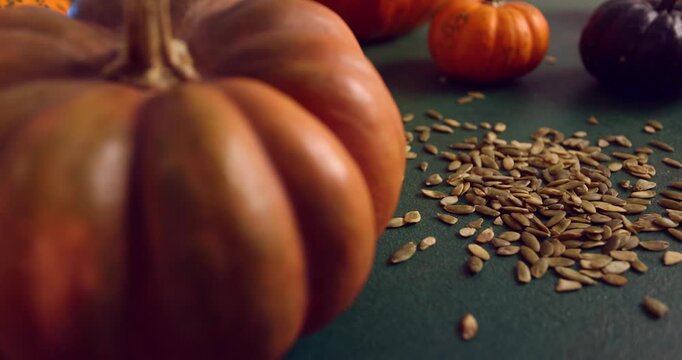 Pumpkin Seeds Falling onto Dark Green Table