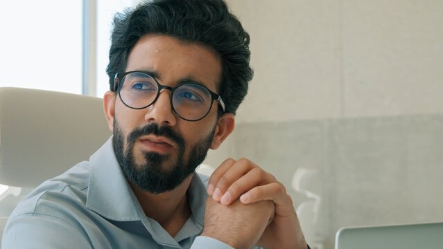Thoughtful pensive Arabian businessman Indian man entrepreneur working computer in office analyzing online business project thinking solving problem brainstorming male manager work strategy planning