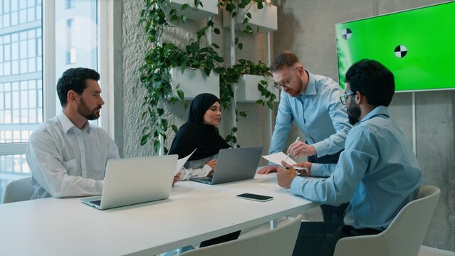 Multiethnic business team discussing documents presentation office meeting leader corporate employees businessmen muslim in hijab businesswoman reviewing green screen chroma key conference copy space