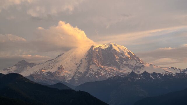 View of Mount Rainier with snow-capped peaks and clouds at sunset in Pierce County, Washington, United States.