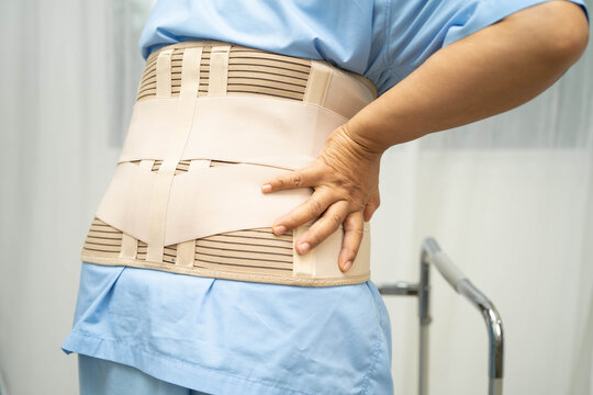 Asian senior pain back wearing elastic support belt with walker.