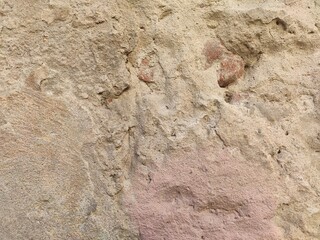 Pitted Rosy Stucco Highly textured irregular facade with warm undertones for historical building articles ancient architecture themes and rustic backgrounds © Tapasii