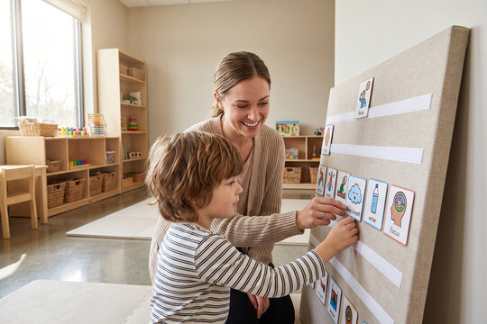 Preschool Teacher Helping Child Arrange Visual Routine Board