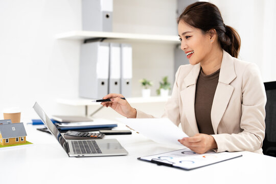 Business woman real estate agent, doing paperwork with laptop for investment strategy, review or planning.