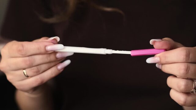 Woman displays pregnancy test in hands, highlighting the gradual appearance of test lines in a close-up view with soft lighting