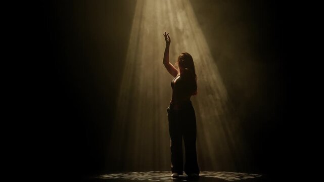 A woman dances with outstretched arms under golden stage light on a dark smoky floor. Concepts related to dance, self discovery, album covers, singles, or podcasts