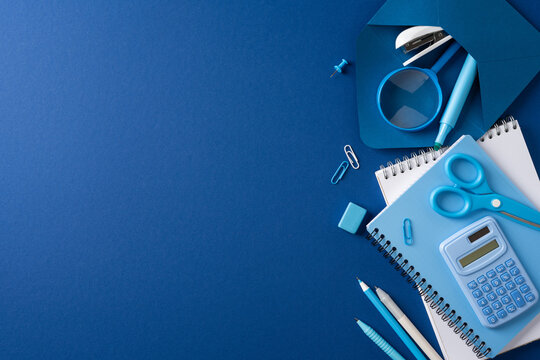 Back to school blue stationery flat lay with notebook, pen, calculator and scissors on desk