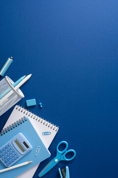 Back to school flatlay with blue stationery, notebook, calculator and scissors on textured vertical background