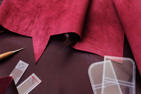 Tools for cutting leather. Genuine burgundy leather for manufacture of products and accessories. High-quality leather. Manufacture of accessories made of natural or artificial leather. Handmade work. 