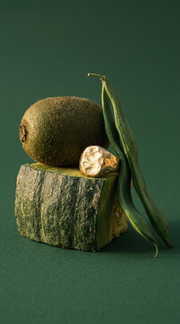 Contemporary jewelry photography of hammered gold signet ring with whole kiwi fruit and green bean pods on pumpkin slice