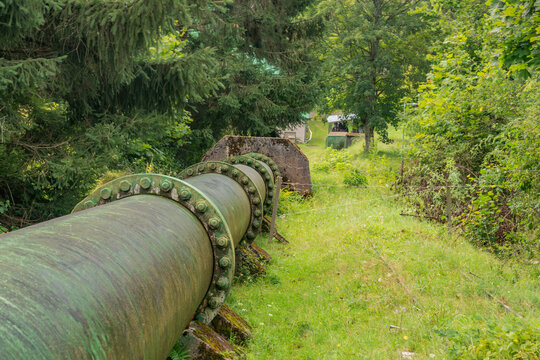 View of the Jasenie Hydroelectric Power Plant featuring a large industrial pipeline running through a lush green forest in Jasenie, Banska Bystrica Regio, Slovakia.
