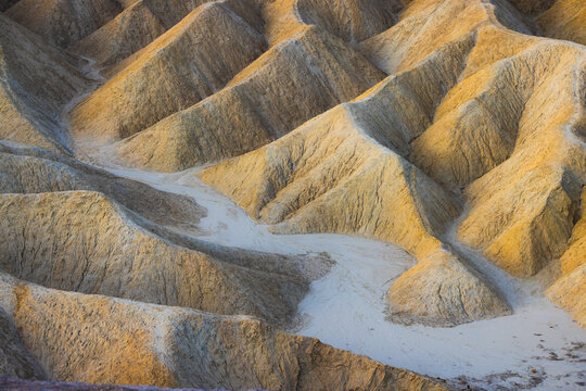 View of the golden-hued eroded badlands and ridges of Zabriskie Point in Death Valley National Park, United States.