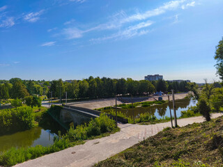 Fototapeta premium Scenic View Of River With Bridge Surrounded By Green Trees And Sky