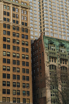View of historic brick buildings with ornate green copper architectural details and a modern skyscraper in the background in New York, New York, United States.