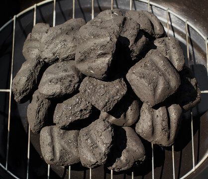 Charcoal briquettes arranged on a barbecue grill before lighting and cooking outdoors.