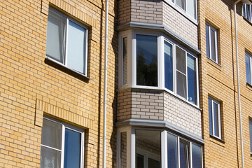 Obraz premium Brick apartment building. Red brick house with windows. City apartment building with a balcony, wallpaper.