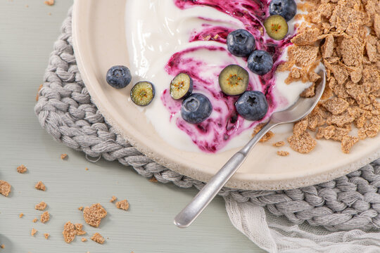 Healthy breakfast bowl with creamy yogurt, blueberry swirl, fresh berries, and whole-grain cereal flakes