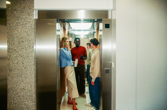 Business professionals conversing in office elevator film photo