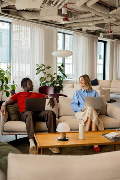 Business lounge meeting with man and woman working on laptops